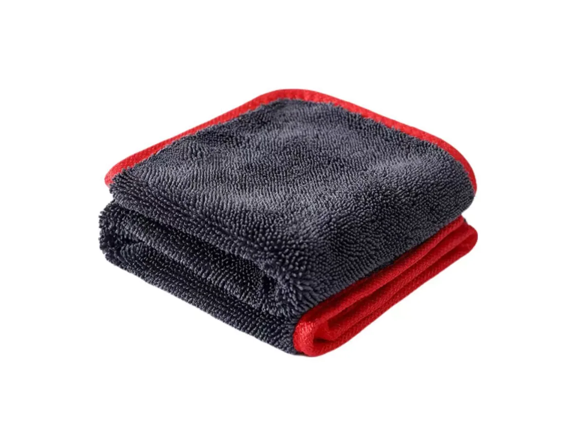 Folded dark gray detailing towel with red edging on a white background