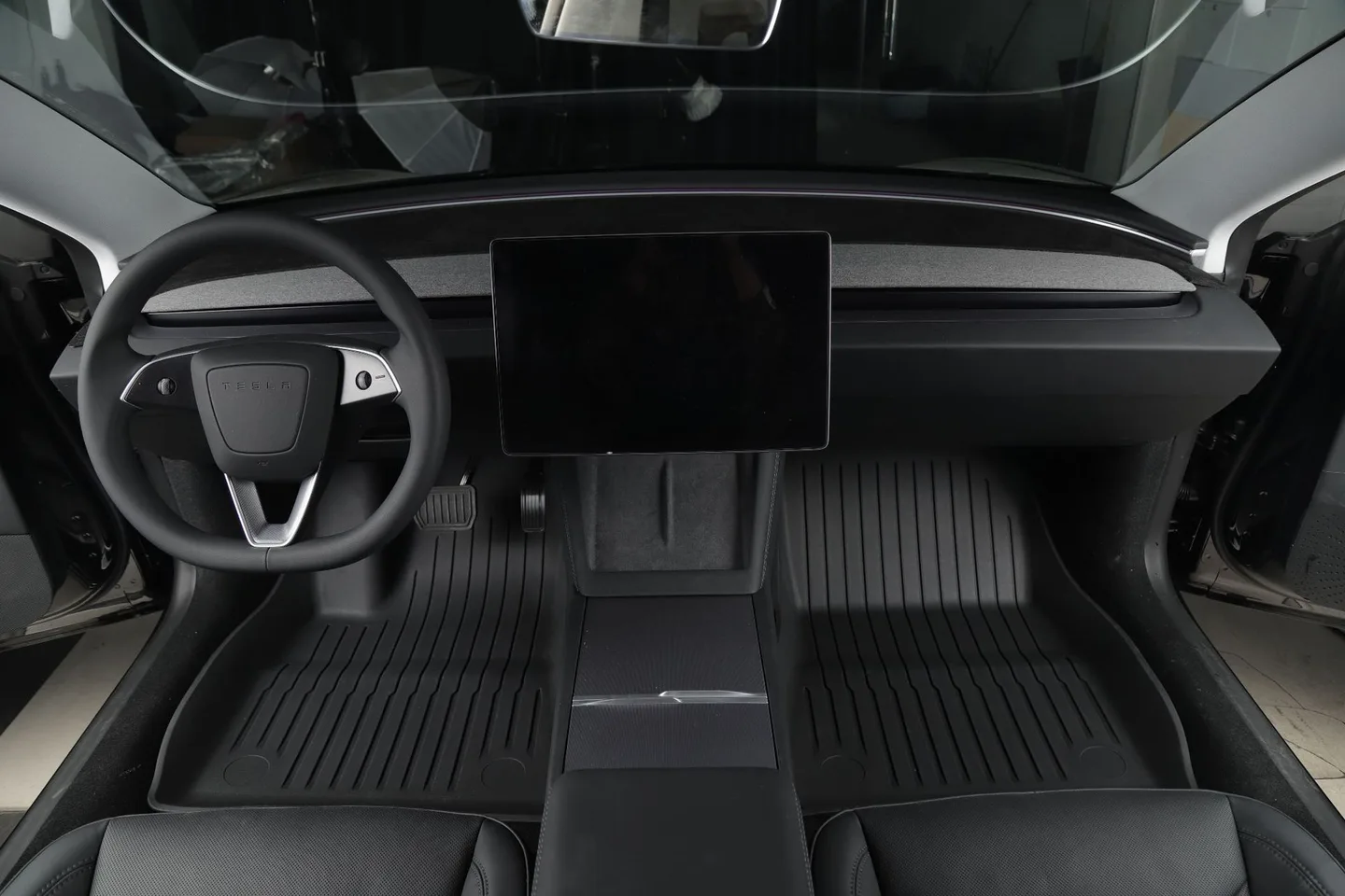 Floor mats installed in a vehicle cabin, viewed from the open driver door